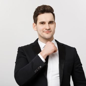 Business Concept: Smiling thoughtful handsome man standing on white isolated background and touching his chin with hand.