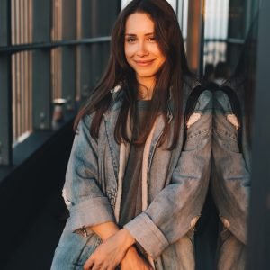 Portrait of a young attractive emotional girl dressed in a trendy blue denim coat, look at the camera