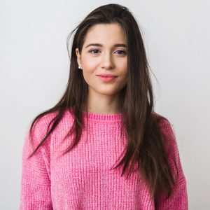 young and beautiful woman in pink warm sweater, natural look, smiling, portrait on white studio background, isolated, long hair